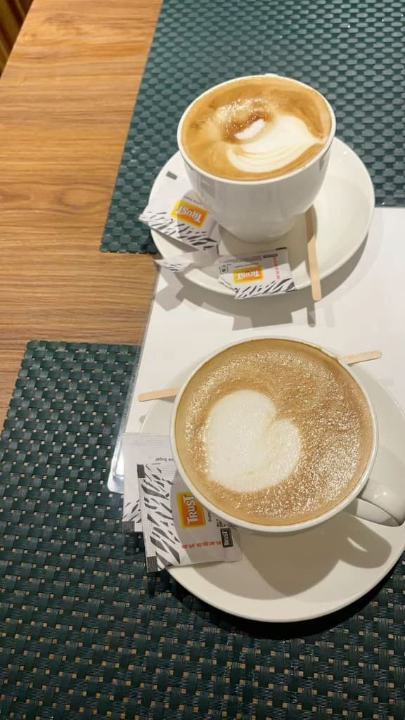 Two cups with latte art on emerald placemats